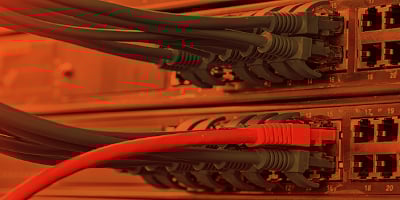 Orange-tinted photographic close-up up cabling plugged into a network switch.